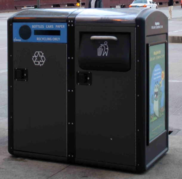 Trash cans with recycling symbol and slots to deposit bottle, paper, cans, and trash