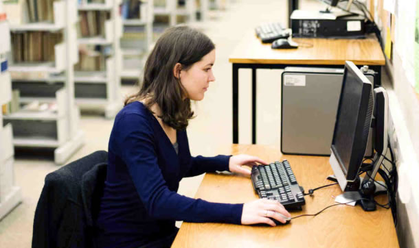 Teen using a public computer in the library setting.