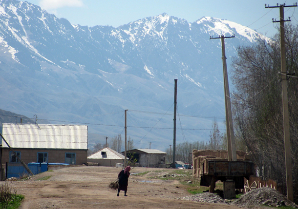 Photo: a woman walking on a dirt road, with mountains in the background