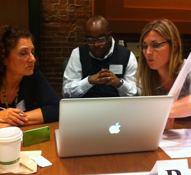 A team of three people working around a laptop computer